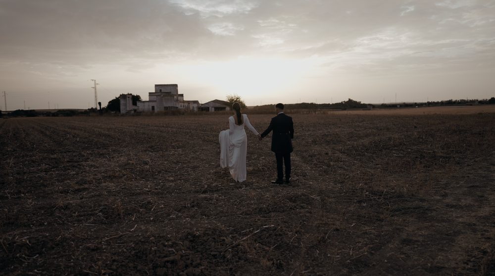 Ana y David de la mano por el campo al atardecer, con la Hacienda Ballemari al fondo