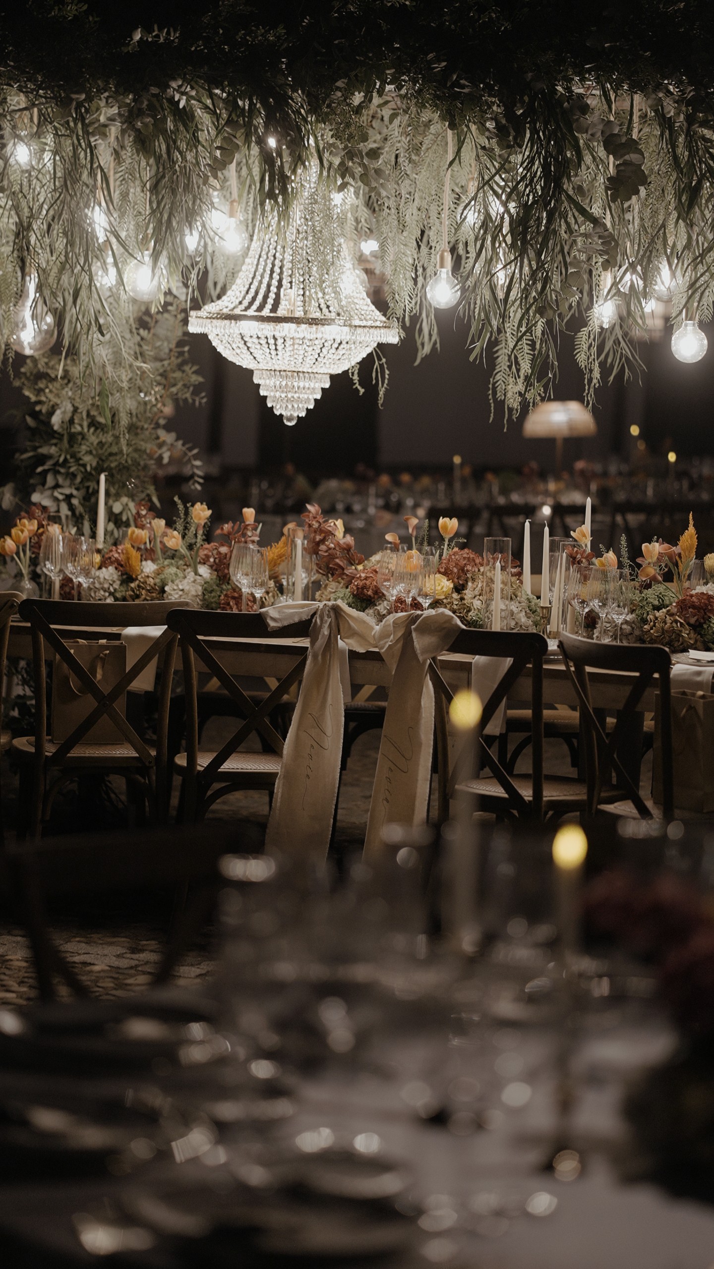 La mesa del banquete bajo una lámpara de araña y guirnaldas de luces, en la Hacienda Ballemari