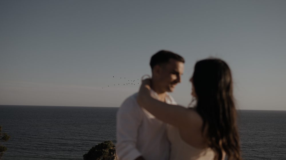 Ana y David abrazados frente al mar de Cádiz al atardecer, en su postboda