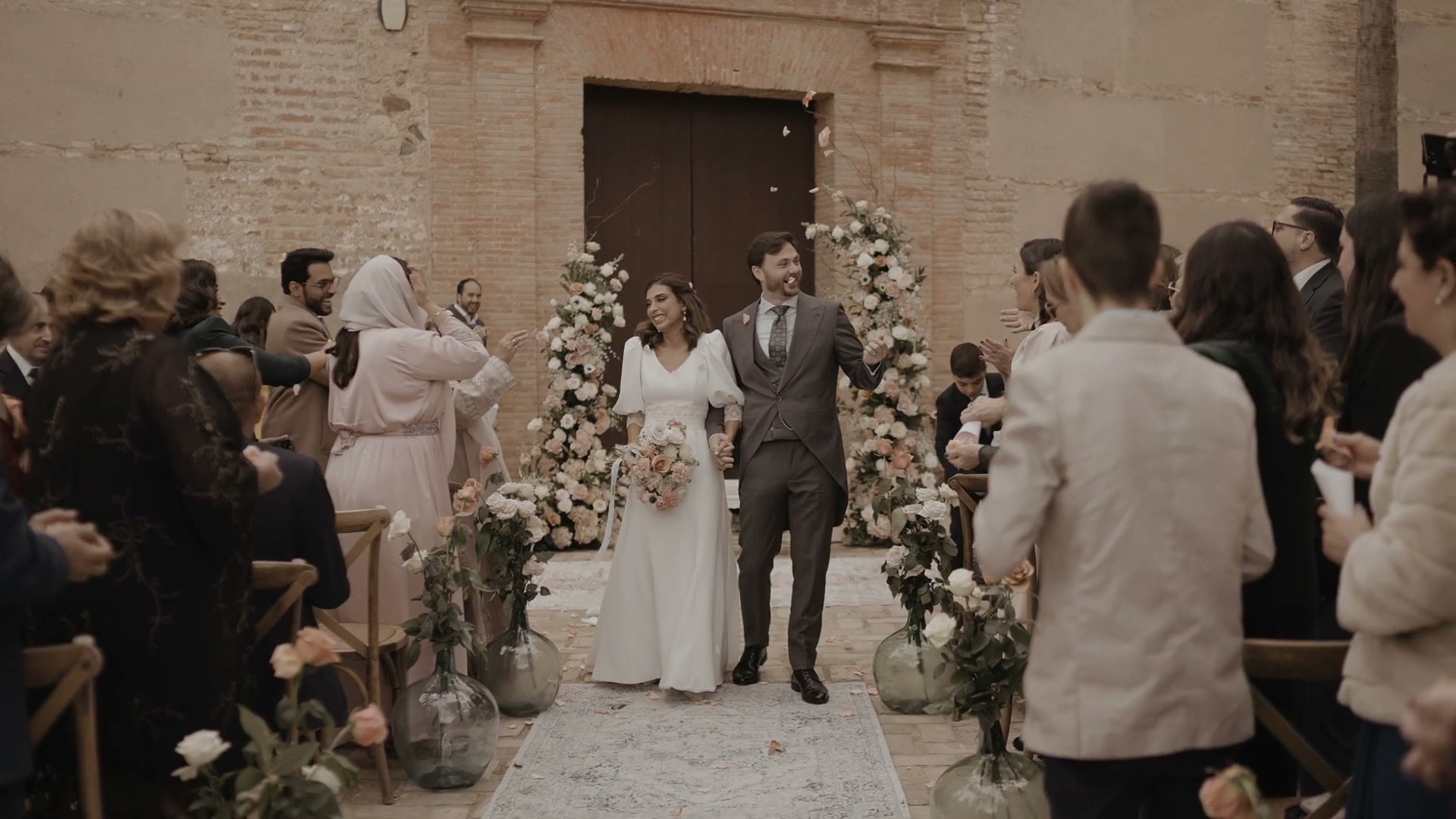 Juan y May salen de la ceremonia por el pasillo, entre sus invitados, con los arcos de flores a la puerta de la iglesia