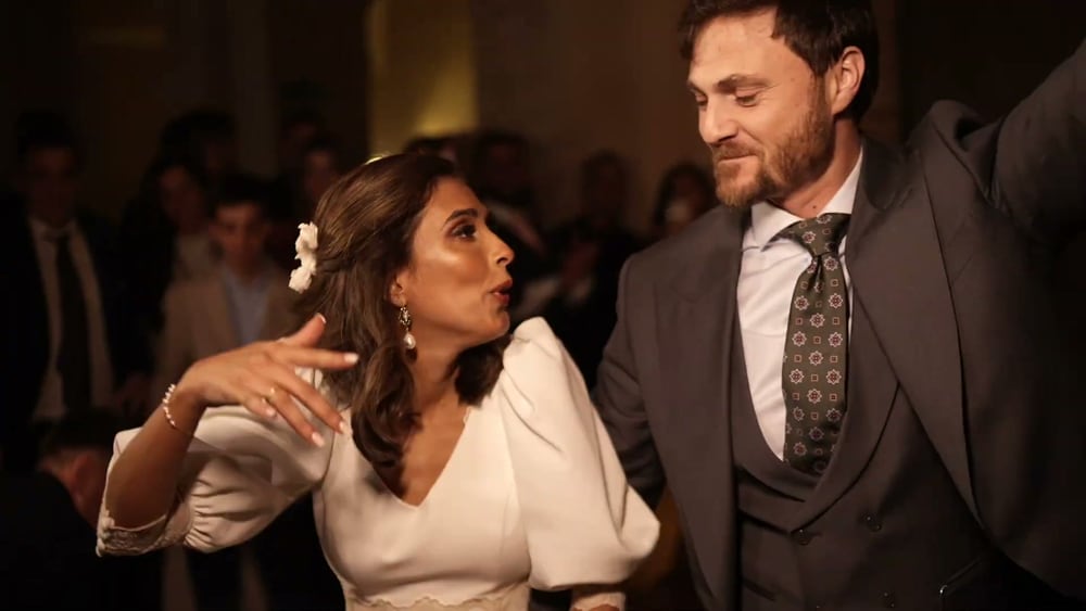 May, con una flor en el pelo, y Juan bailan muy juntos, riéndose, de noche