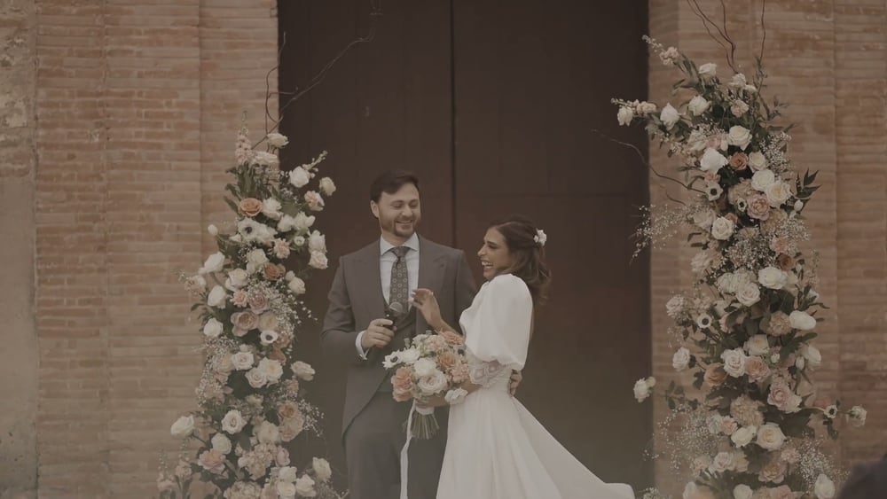 Juan y May se miran a la puerta de la iglesia, entre dos columnas de flores, ella con su ramo