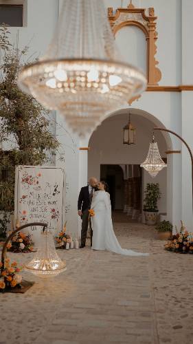 Rocío y Juan bajo el arco de entrada del Convento de la Luz, junto al cartel «Mientras uno esté vivo, uno debe amar lo más que pueda»