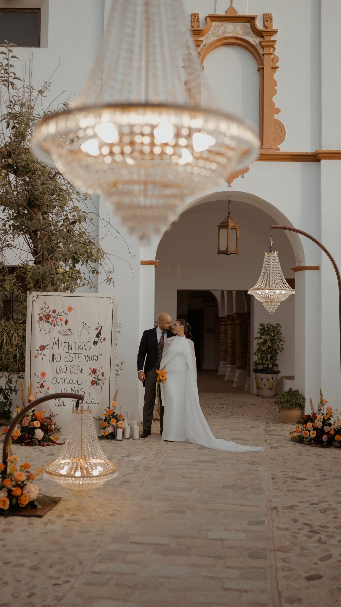 Rocío y Juan bajo el arco de entrada del Convento de la Luz, junto al cartel «Mientras uno esté vivo, uno debe amar lo más que pueda»