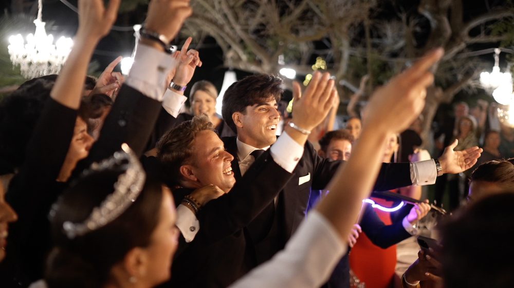 Los invitados bailan con los brazos en alto; Juanma, de traje, en el centro