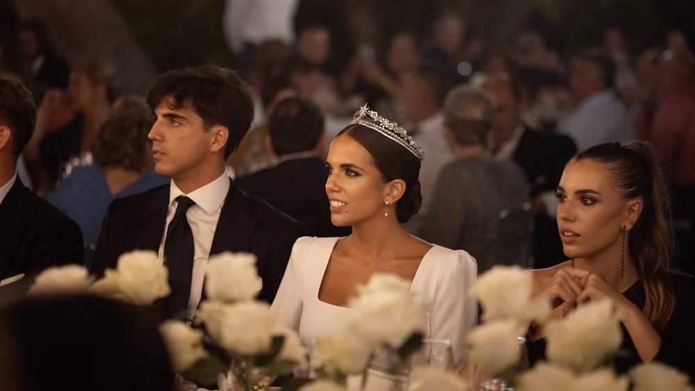 Patri, en la mesa del banquete, entre rosas blancas, mirando hacia un lado