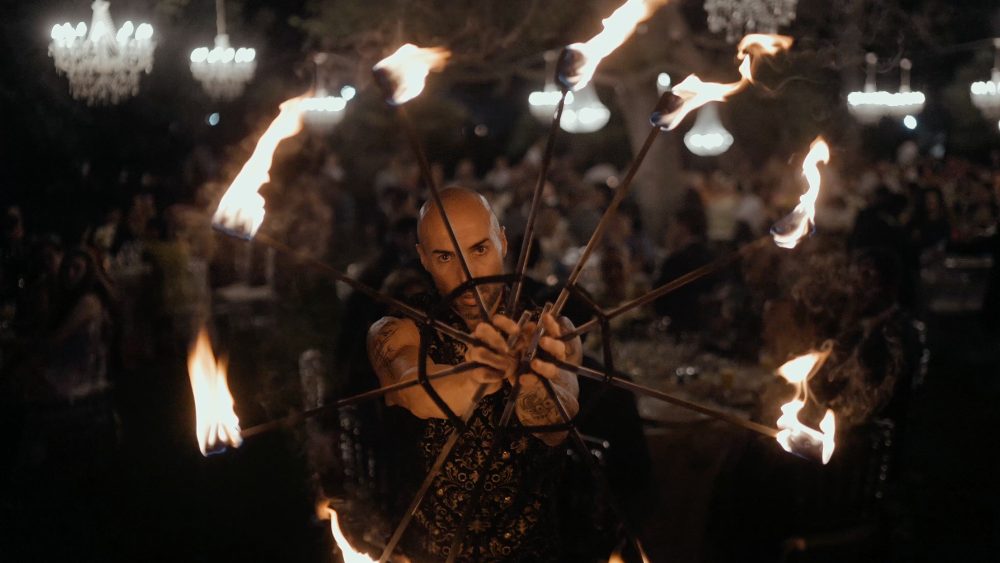 A fire performer spins torches in the middle of the party at night