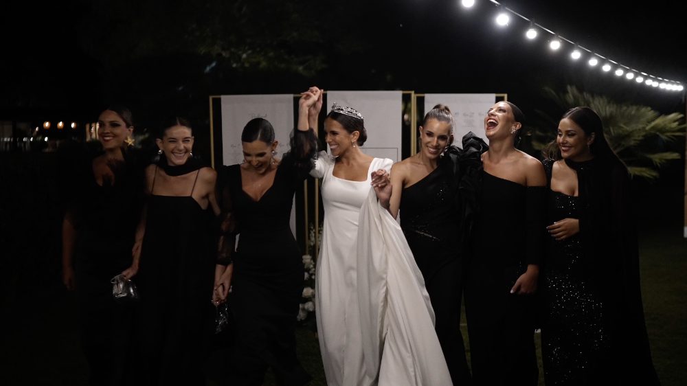 Patri, en el centro, con sus amigas vestidas de negro, riéndose en la fiesta de noche