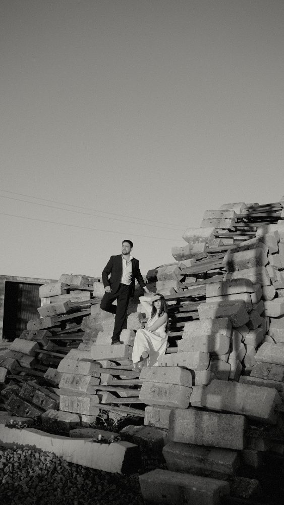 Black and white: he stands and she sits on a pile of concrete sleepers · Gearmedia