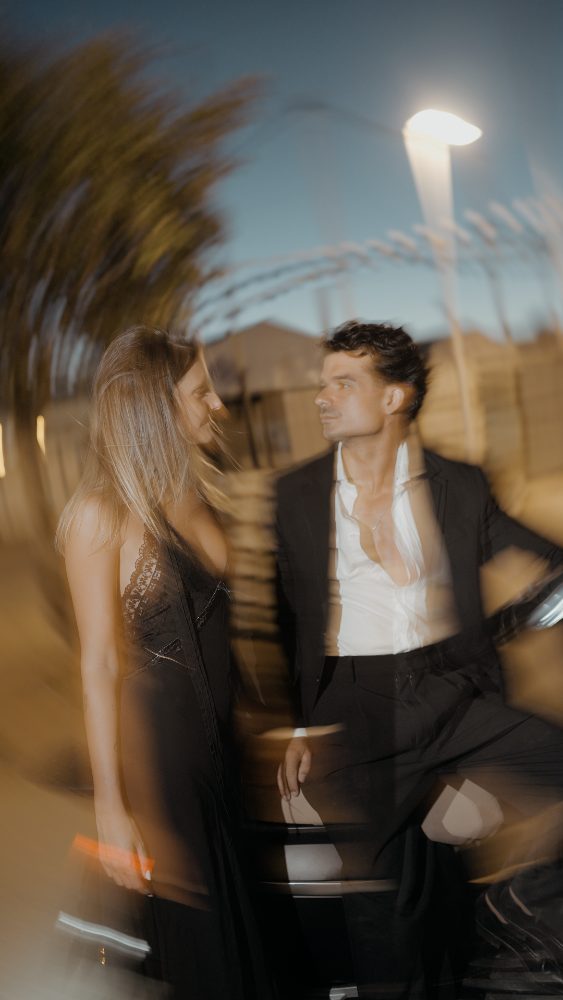 Rocío y Pablo, de negro y blanco, junto a un coche, en una foto movida de noche, con una farola al fondo