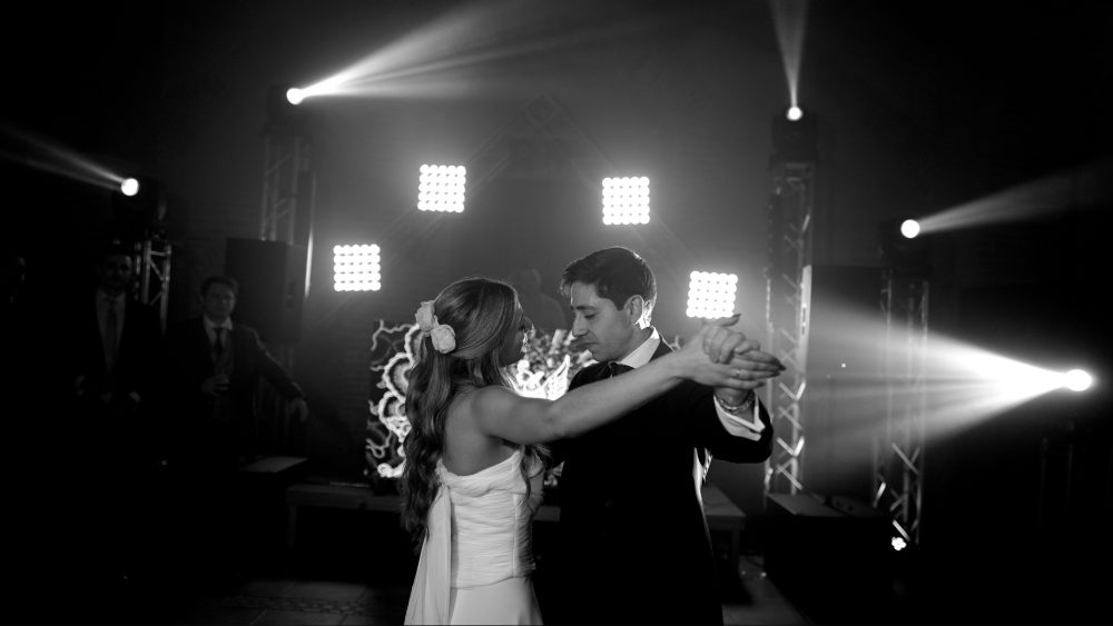 Black and white: the couple dancing in an embrace under stage spotlights · Gearmedia