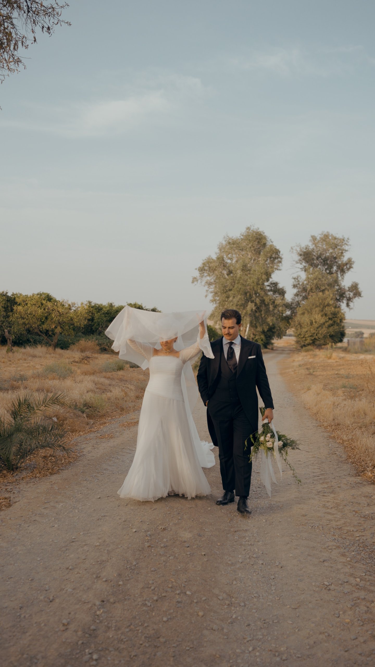 Novia a contraluz junto a una cortina, en penumbra, en una boda en Huelva · Gearmedia