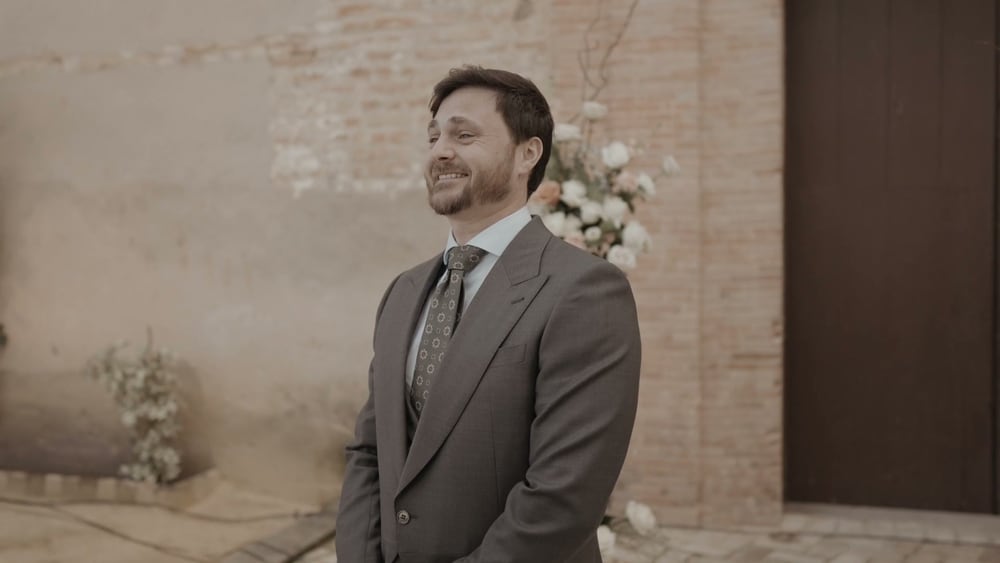 Juan smiles, waiting at the church door of the Convento de la Luz, a floral arch behind him