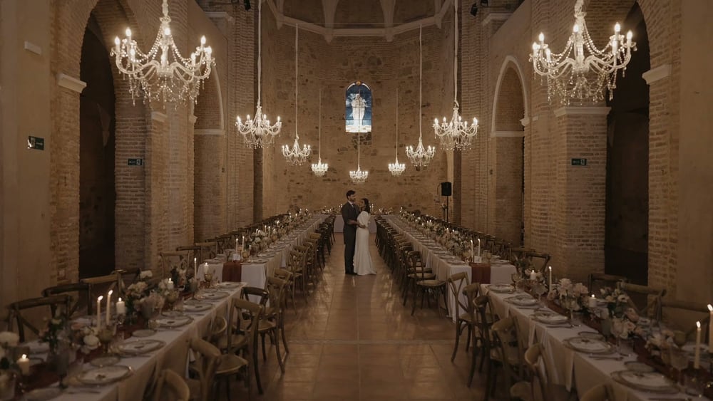 The nave of the Convento de la Luz laid for dinner, long tables under crystal chandeliers, the couple small at the far end