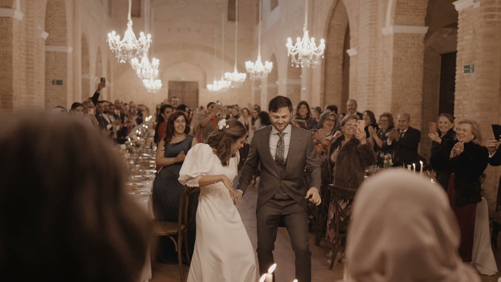 Juan and May dance down the middle of the nave, between the long tables, their guests clapping around them