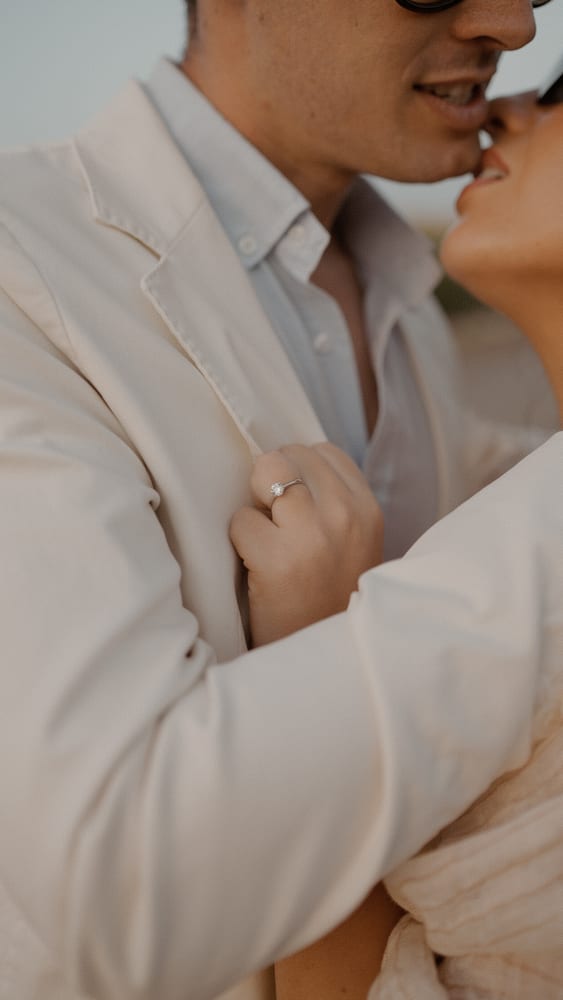 Anillo de pedida en la mano de la novia, abrazada a su pareja · Gearmedia y Cupido debe morir