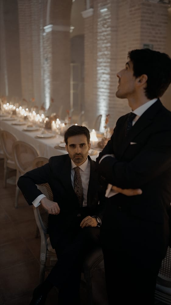 Dos hombres con traje oscuro junto a la mesa del banquete · Gearmedia y Cupido debe morir