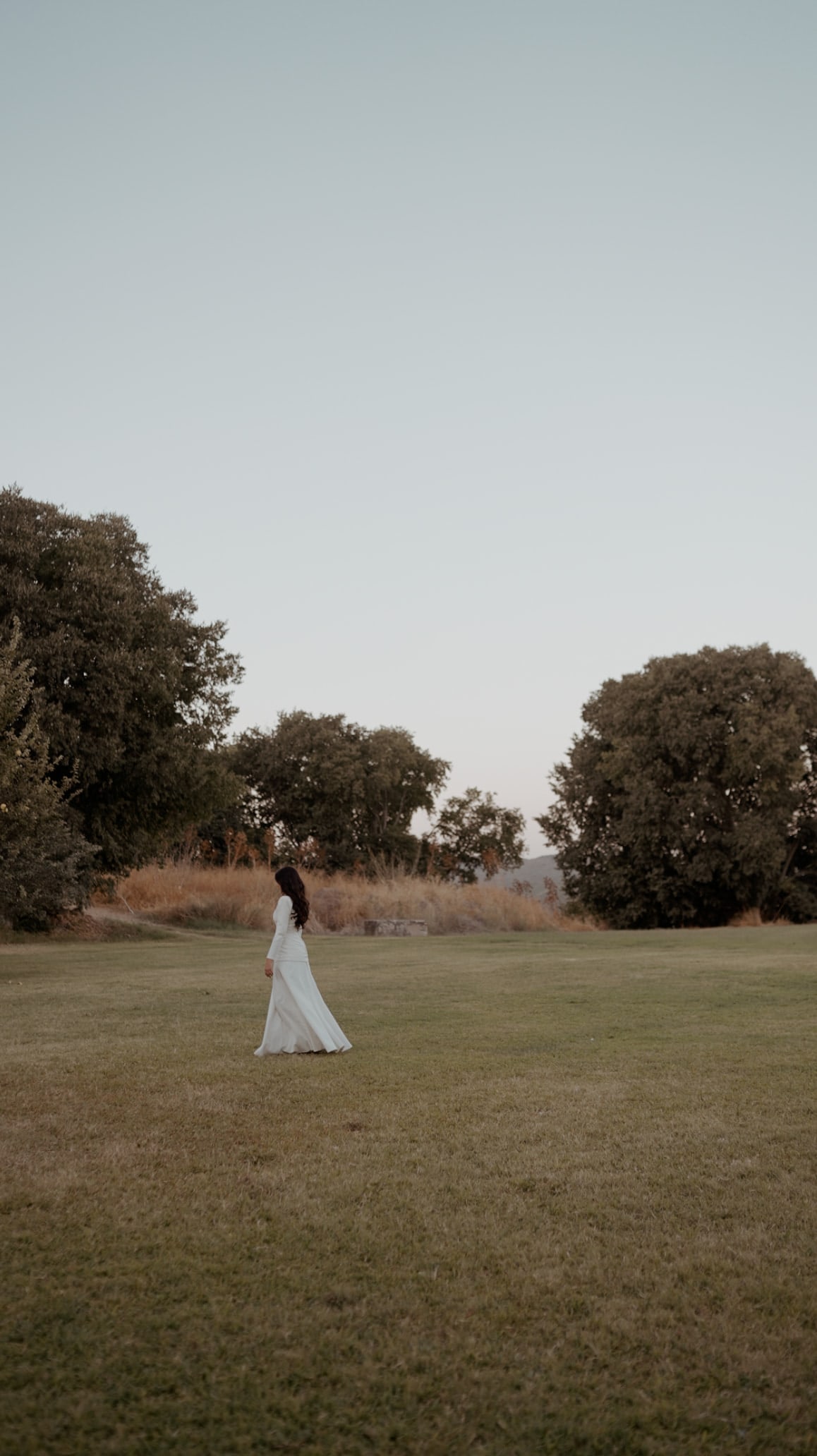 Novia caminando sola por un prado al atardecer, en La Cartuja de Cazalla, Sevilla