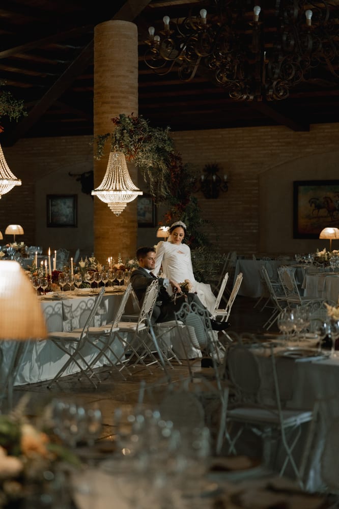 Novios en el salón del banquete, entre lámparas de cristal y velas · Gearmedia y Cupido debe morir
