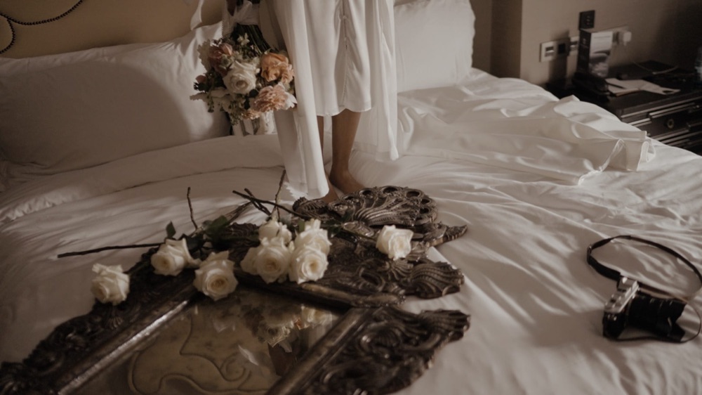 Flowers, an antique mirror and a camera on the bed as May gets ready, at Hotel Alfonso XIII in Seville · Gearmedia