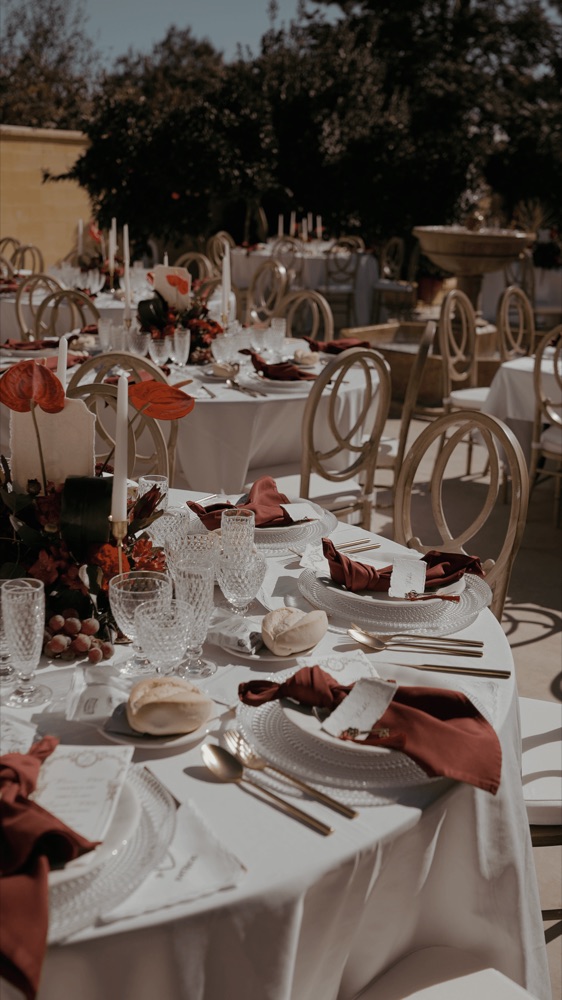 Mesas del banquete al aire libre con servilletas granates, en una boda en Cádiz · Gearmedia