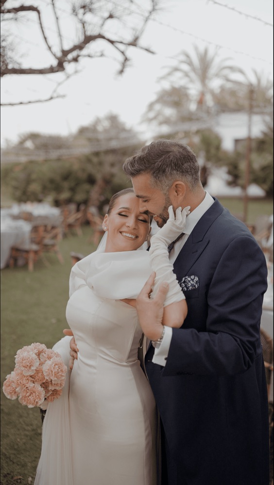 Novio besando la frente de la novia en el jardín del cóctel, en una boda en Huelva · Gearmedia