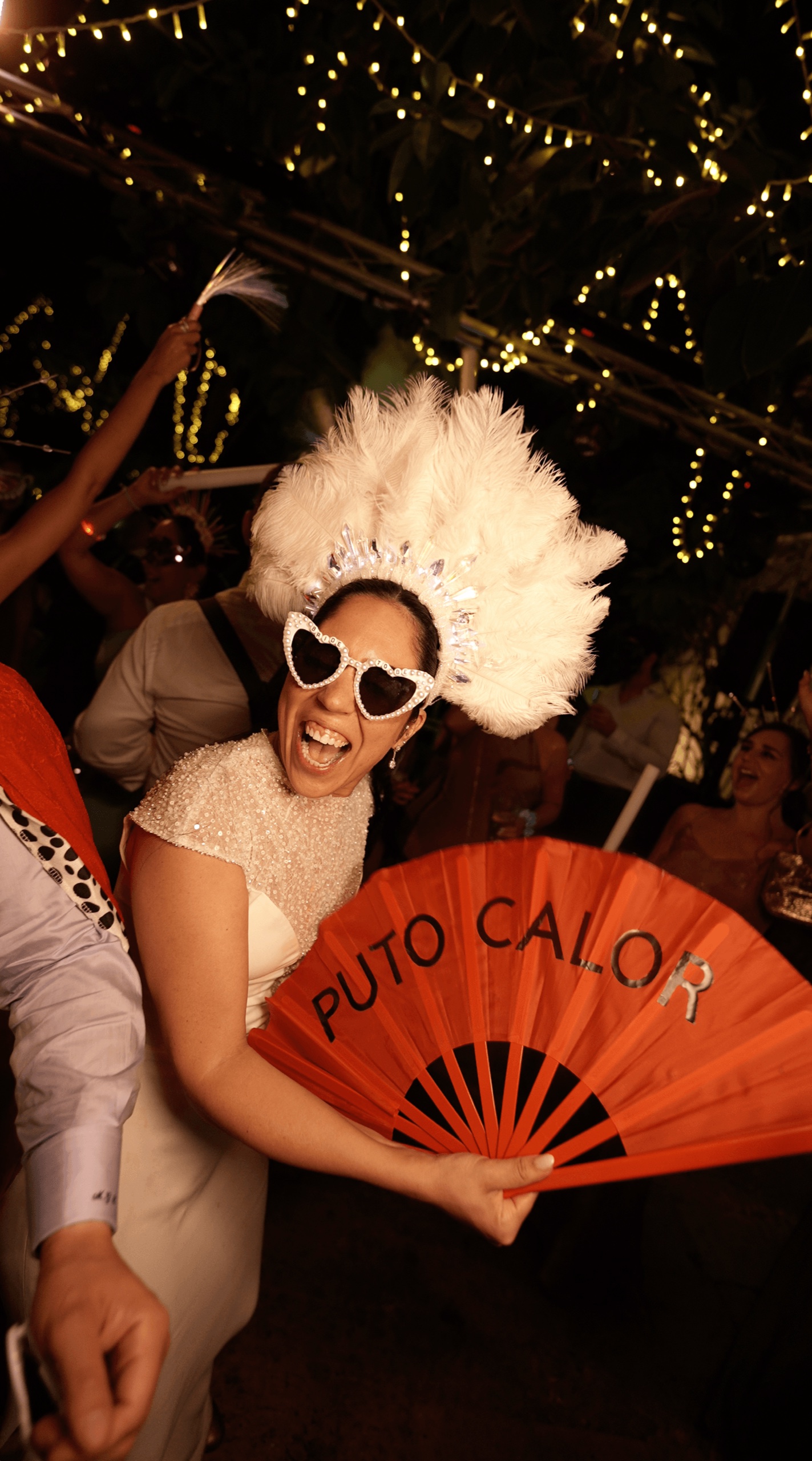 Invitada con tocado de plumas y abanico en la fiesta, en una boda en Sevilla · Gearmedia