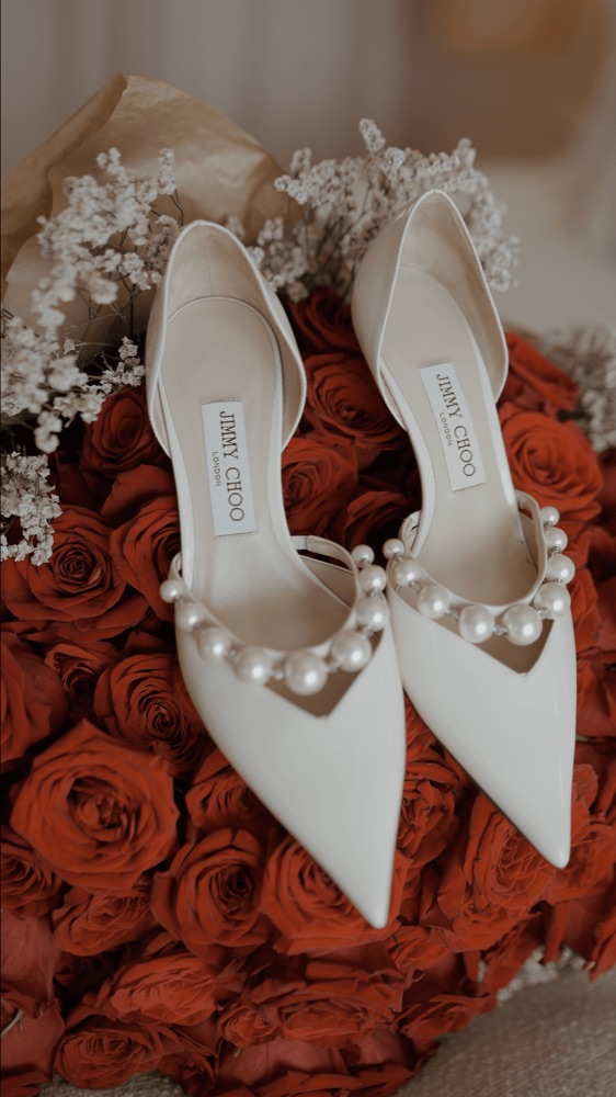 White bridal shoes with pearls on a bouquet of red roses, at a wedding in Seville · Gearmedia