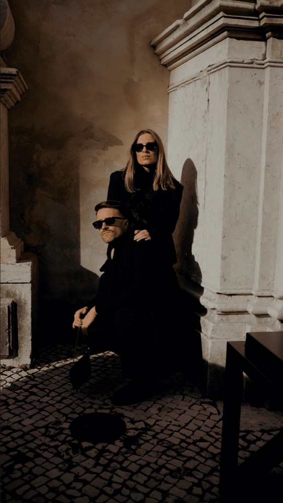 Pareja con gafas de sol posando bajo un soportal de piedra, en una preboda en Sevilla · Gearmedia