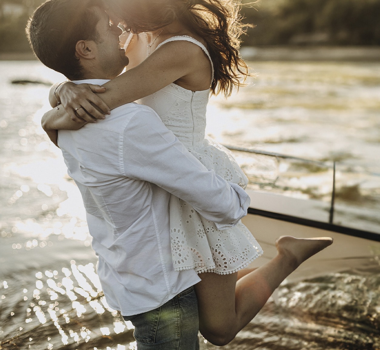 Pareja abrazada junto al río al atardecer, ella en el aire · Gonzalo Lagares