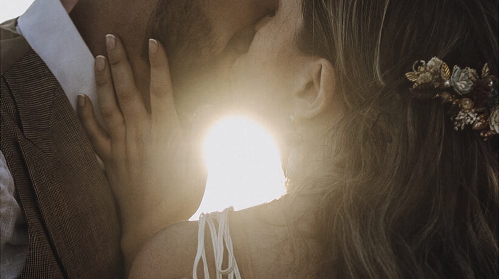 Beso de los novios a contraluz con el sol entre ellos · Gonzalo Lagares