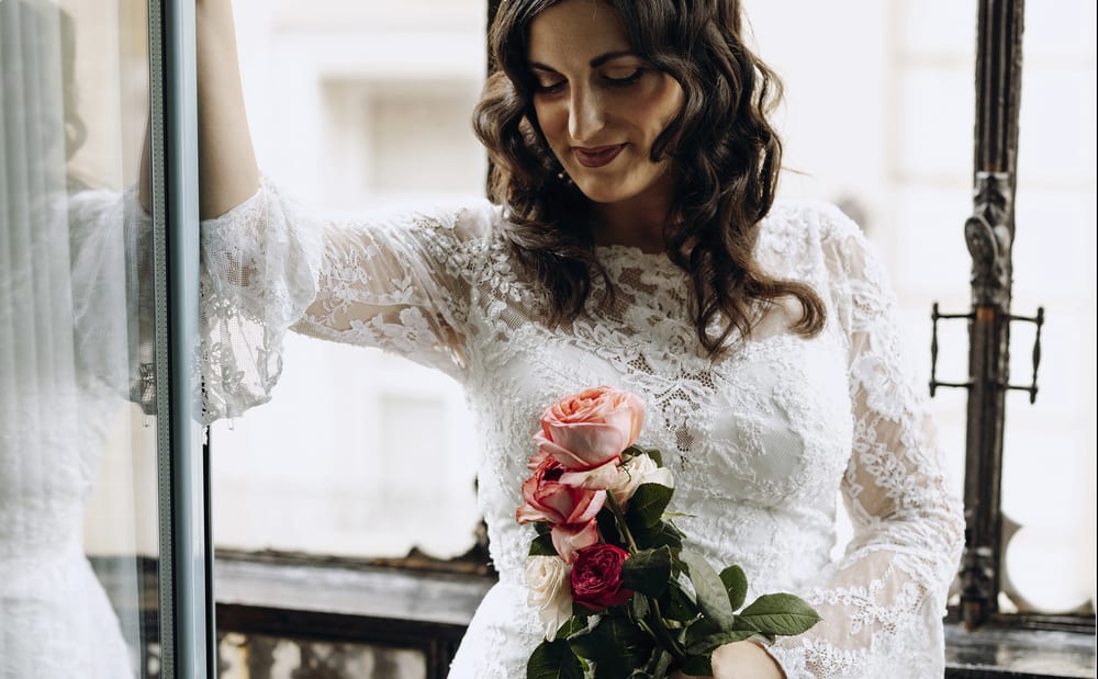 Novia con vestido de encaje en un balcón con un ramo de rosas · Gonzalo Lagares