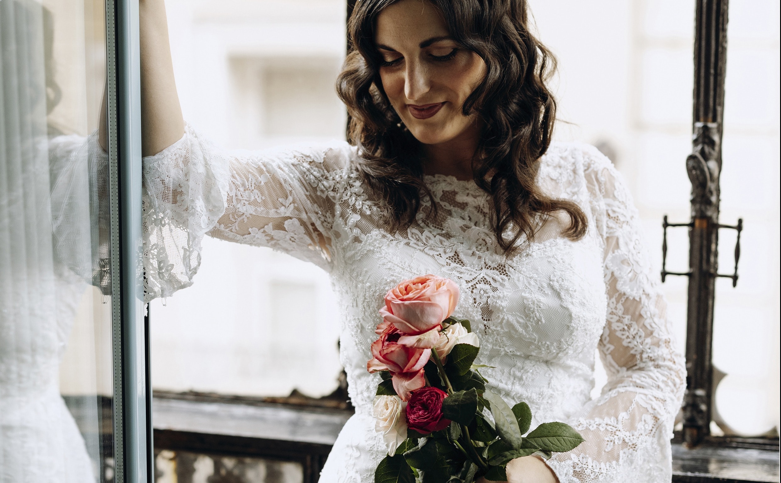 Novia con vestido de encaje en un balcón con un ramo de rosas · Gonzalo Lagares