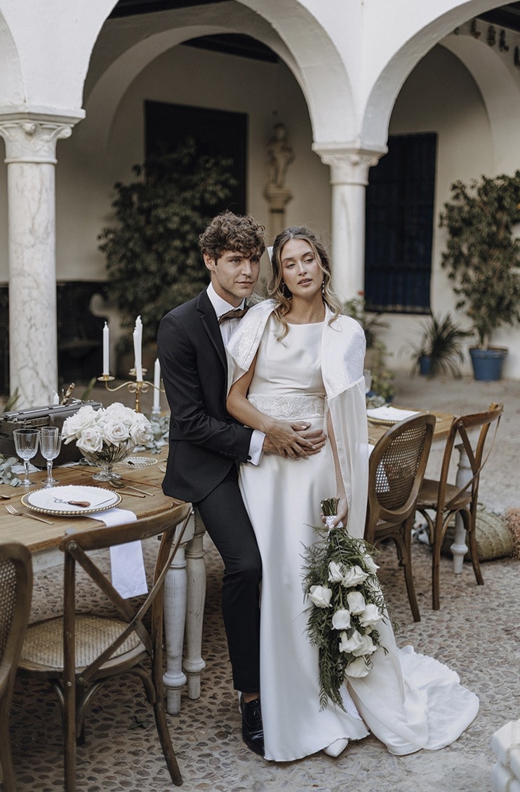 Novios sentados en la mesa de un patio con arcos · Gonzalo Lagares